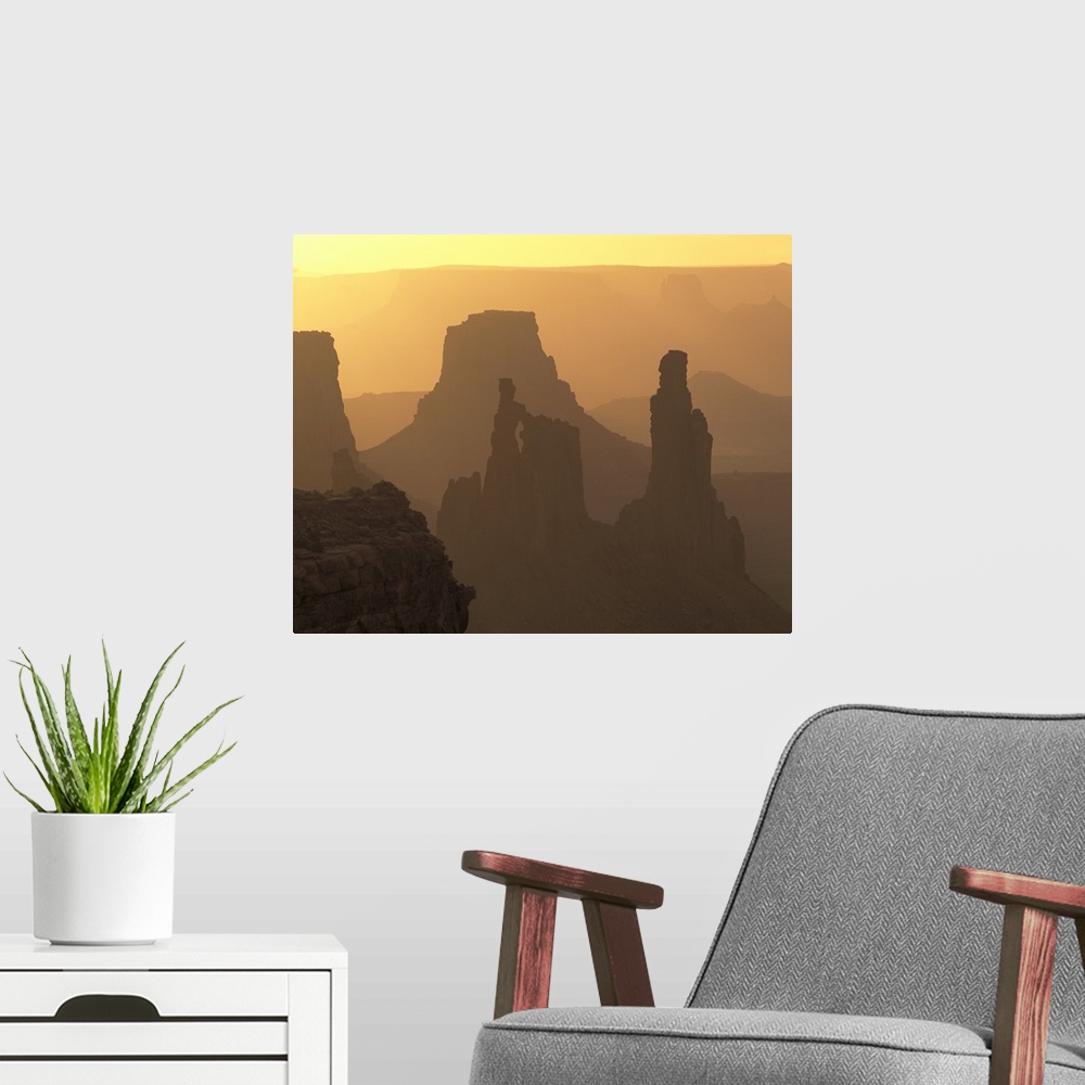 A modern room featuring The large rock formations in Canyonlands National Park is silhouetted by the sunset that is out o...