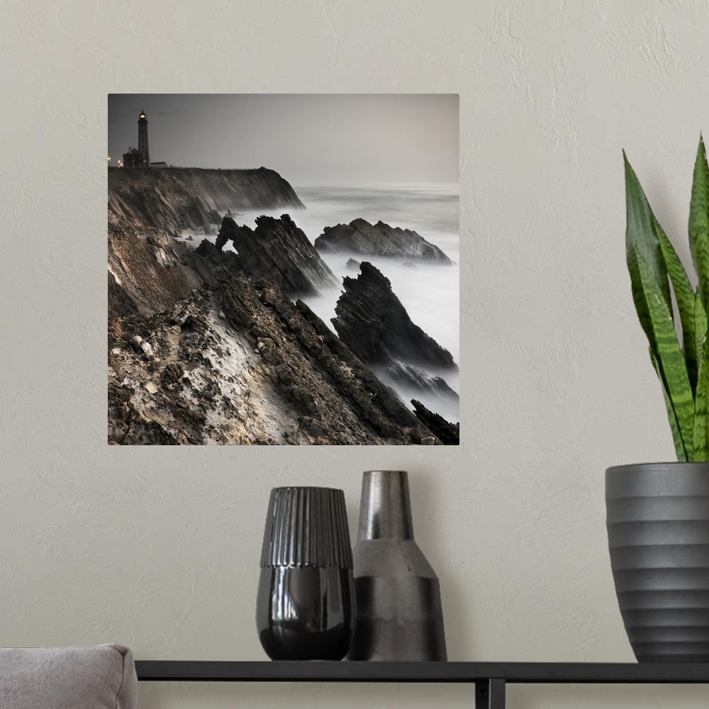A modern room featuring Dynamic photograph of a lighthouse on a foggy jagged rocky coast.