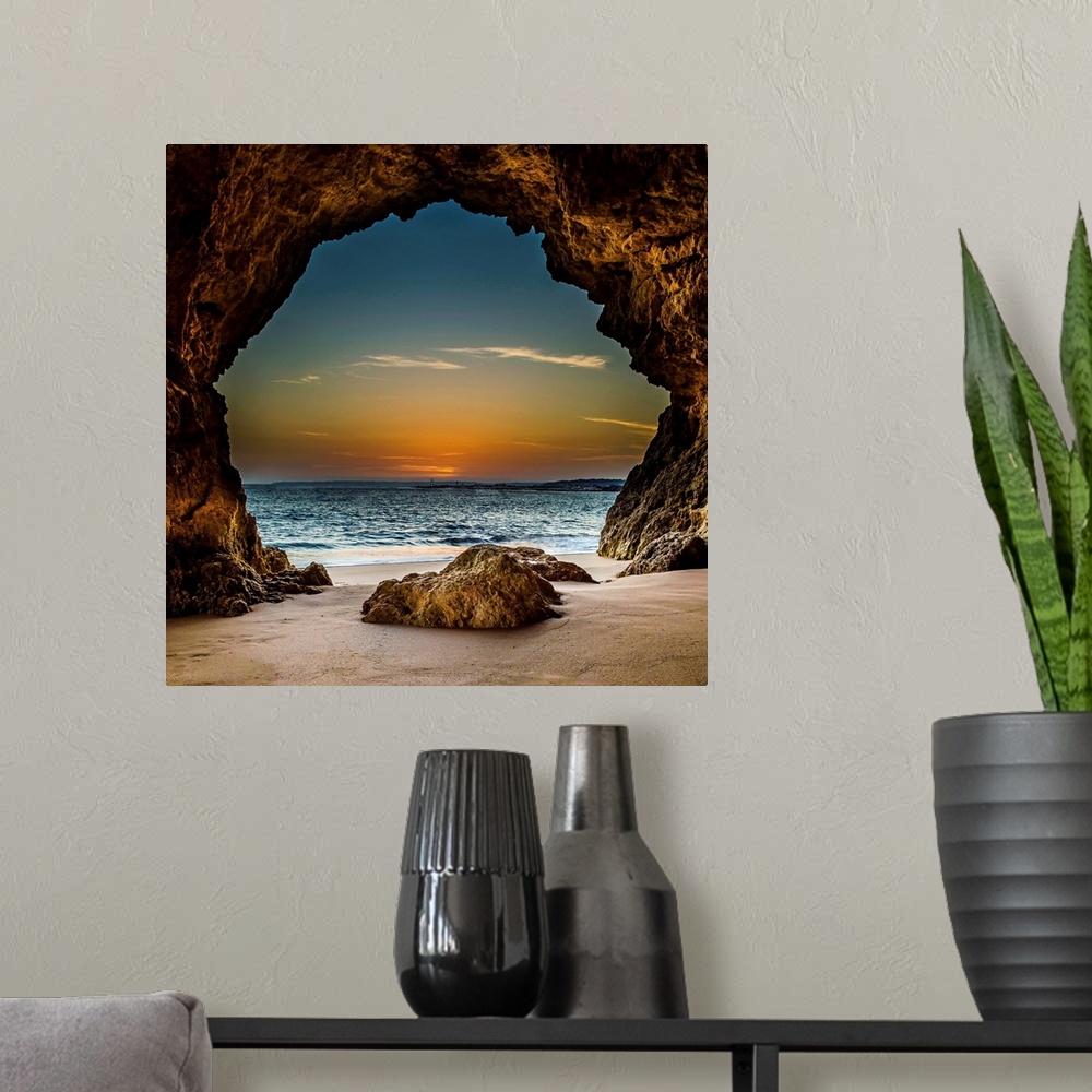 A modern room featuring View from inside a cave on the beach, looking out at the sunset, Ferragudo, Portugal.