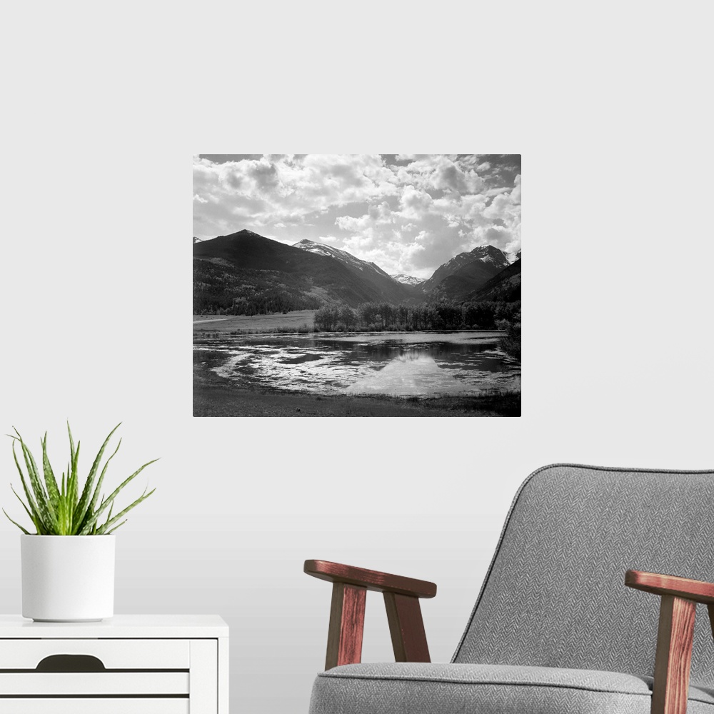A modern room featuring In Rocky Mountain National Park, lake and trees in foreground, mountains and clouds in background.