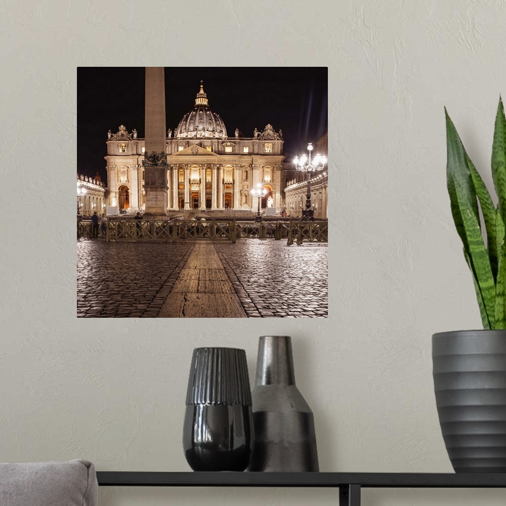 A modern room featuring Square photograph of St. Peter's Basilica  lit up at night.