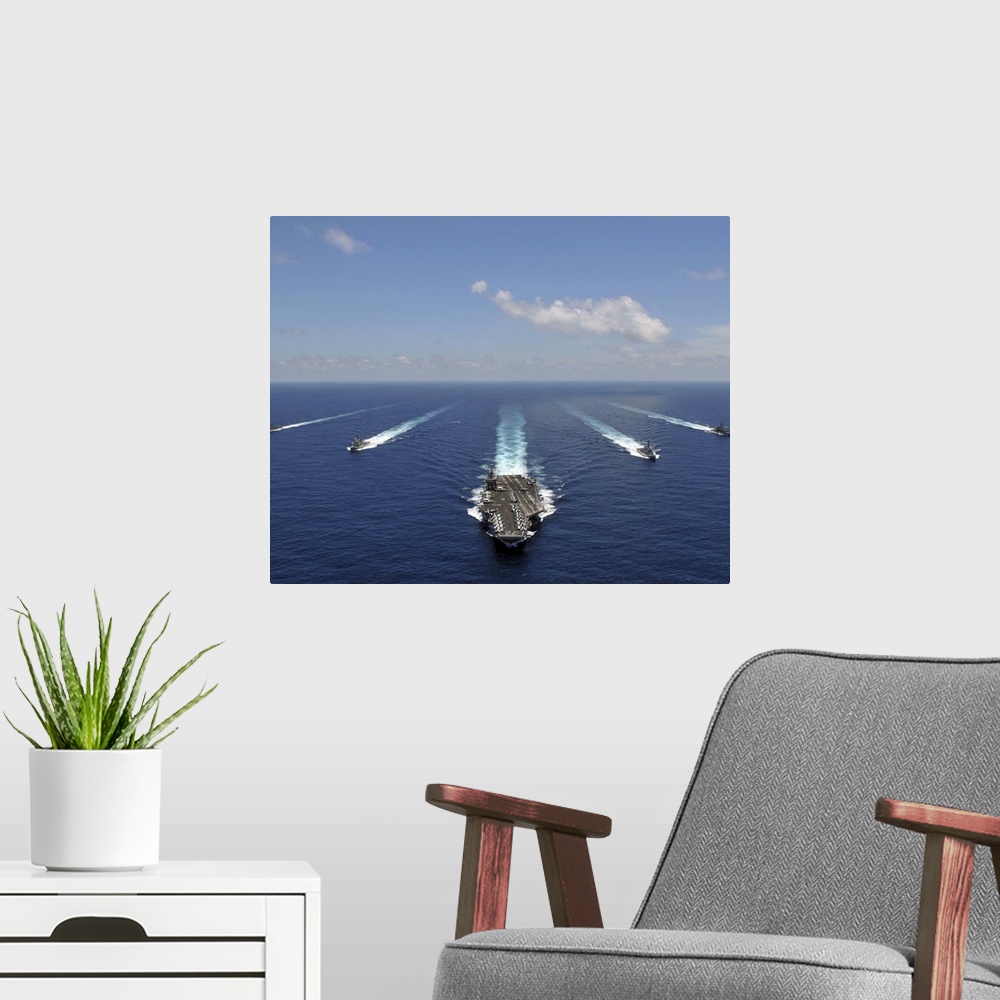 A modern room featuring The aircraft carrier USS Abraham Lincoln leading a formation of ships