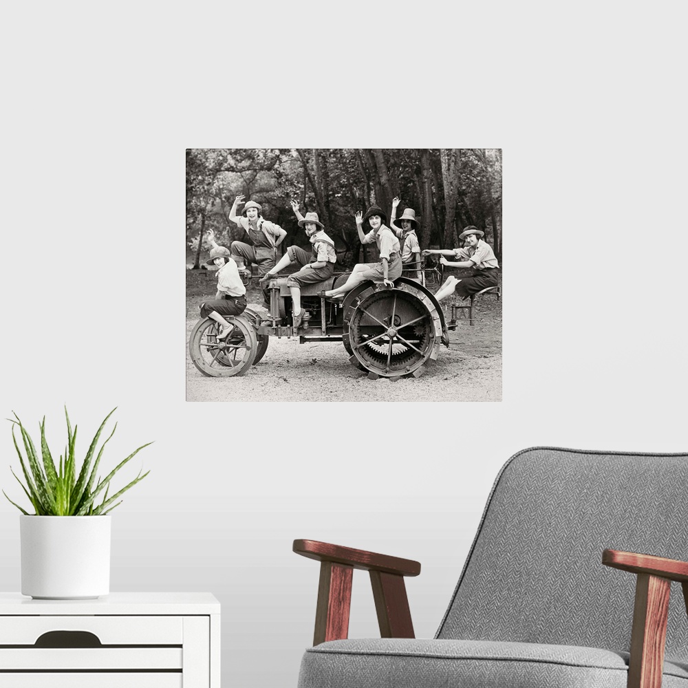A modern room featuring A group of women posing on a tractor in rural America. Photograph, c1925.