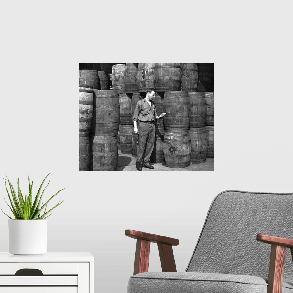 A modern room featuring Stanley Hyams amidst barrels at the Washington Pickle Works in Brooklyn, New York. Photograph, Ro...