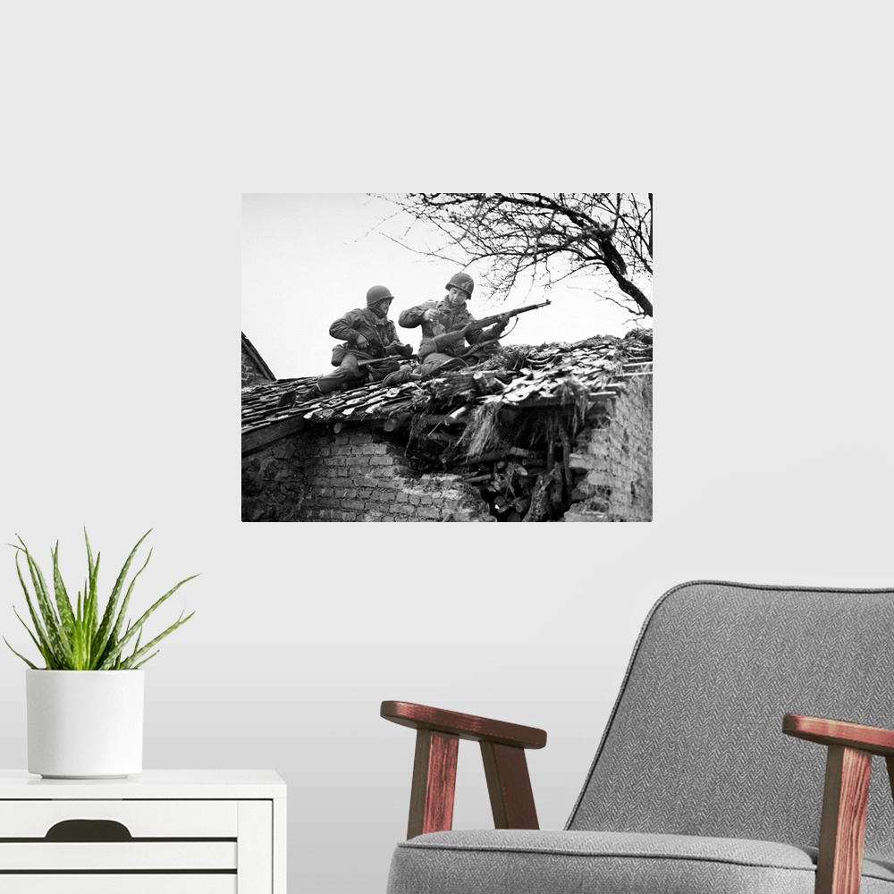 A modern room featuring American rifleman on a rooftop in Beffe, Belgium, snipe German snipers. Photographed 7 January 1945.