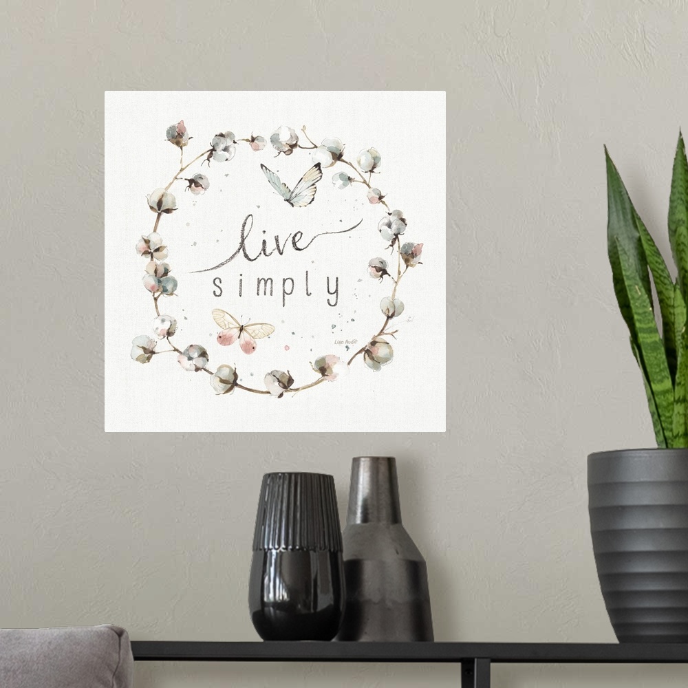 A modern room featuring Decorative artwork of a cotton wreath with the words, live simply, in the center.