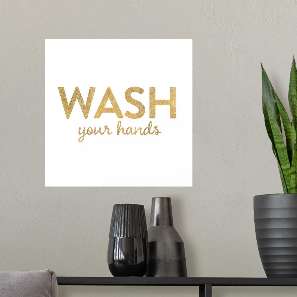 A modern room featuring "Wash Your Hands" written in metallic gold on a solid white background.