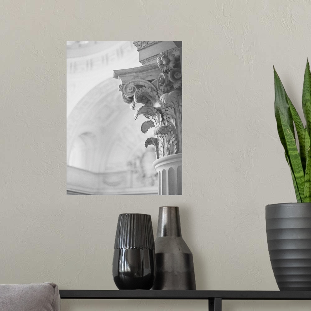 A modern room featuring A black and white photograph of the detail of an architectural column featuring scrolls, daisies ...