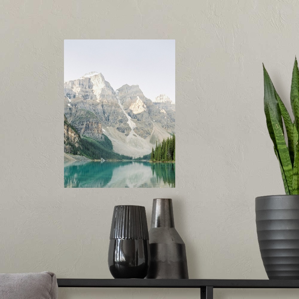 A modern room featuring A vertical photograph of the mountains and trees reflected in Moraine Lake, Banff national park, ...
