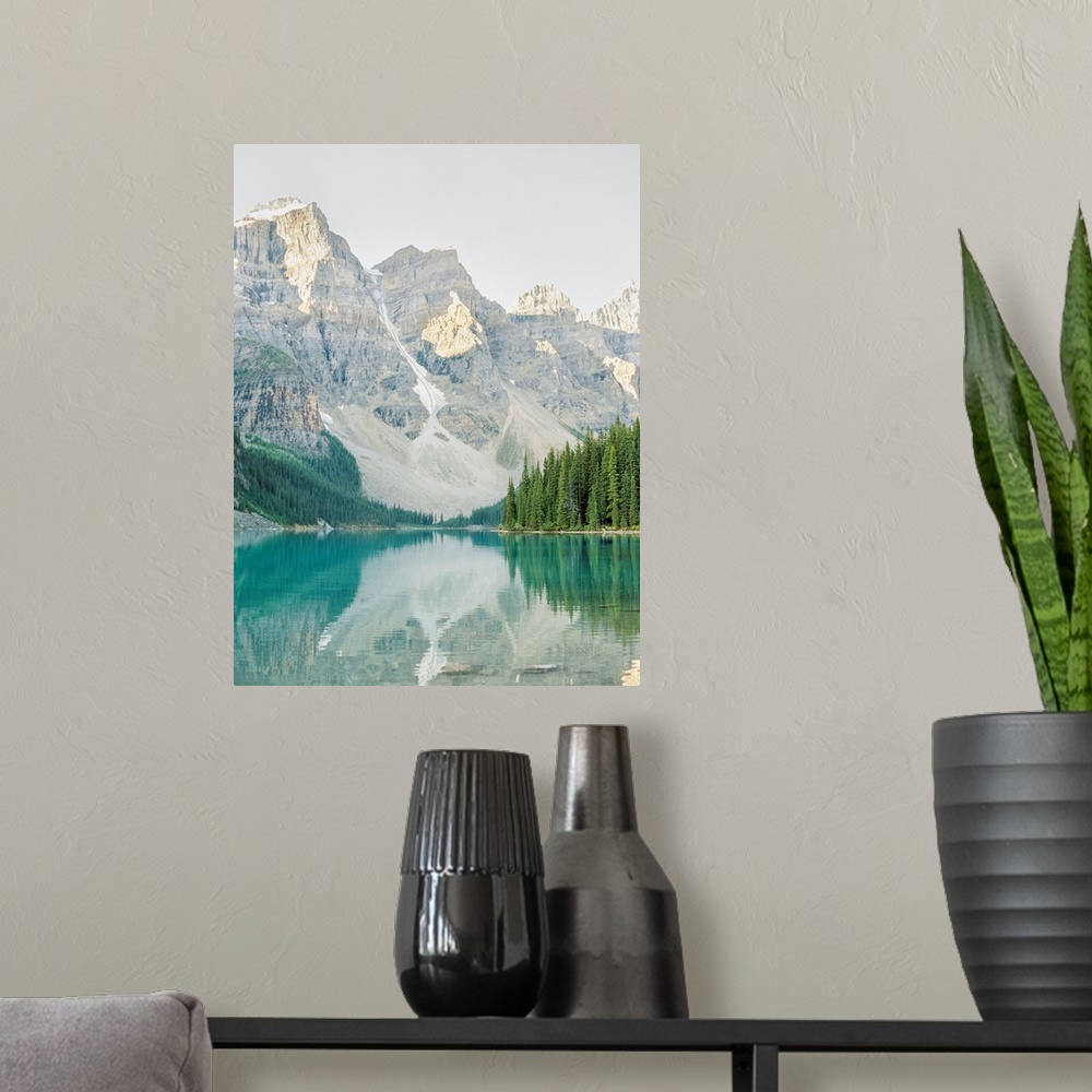A modern room featuring A vertical photograph of the mountains and trees reflected in Moraine Lake, Banff national park, ...