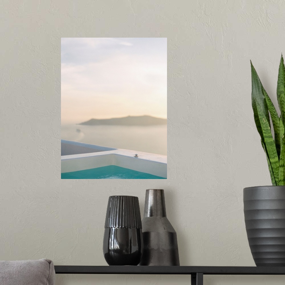 A modern room featuring Photograph of the edge of a swimming pool with an island in the distance, Santorini, Greece.