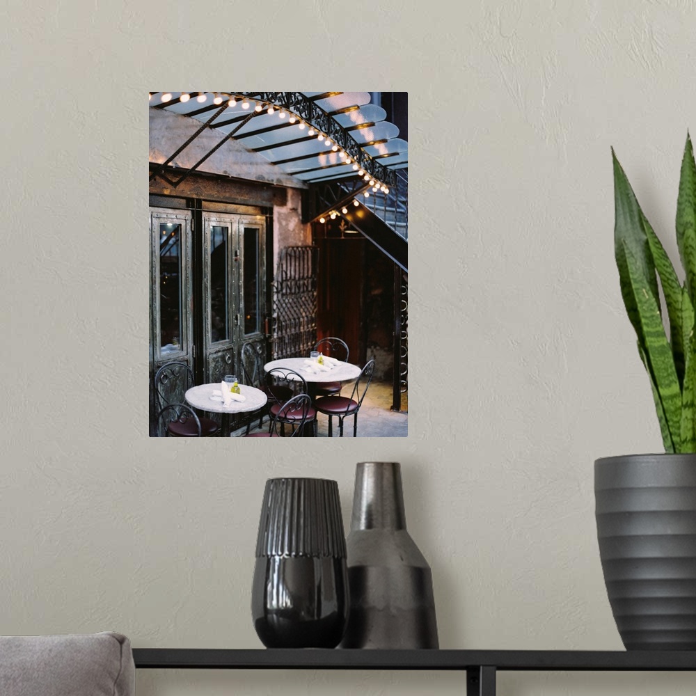 A modern room featuring A photograph of the tables and lights of a rustic mediterranean cafe.