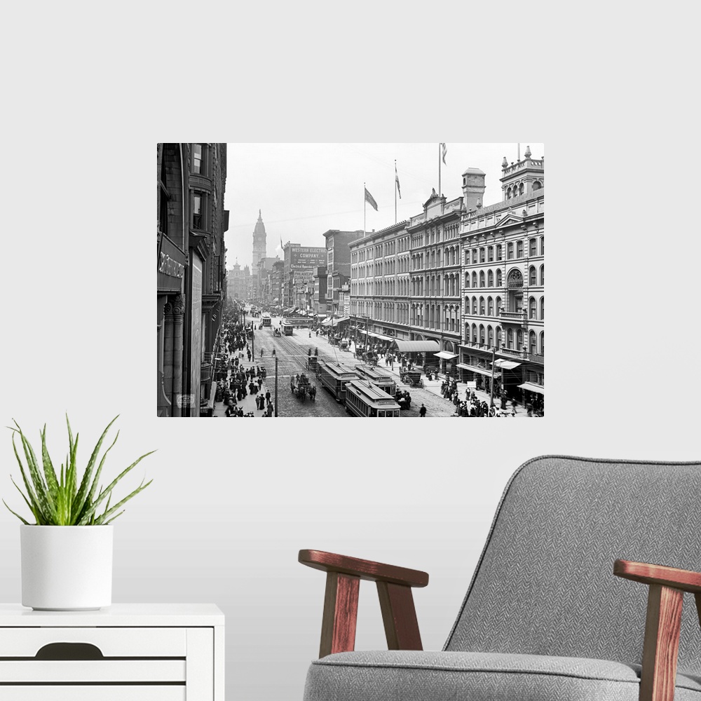 A modern room featuring Antiqued canvas photo print of old buildings with street cars and horses traveling through the mi...