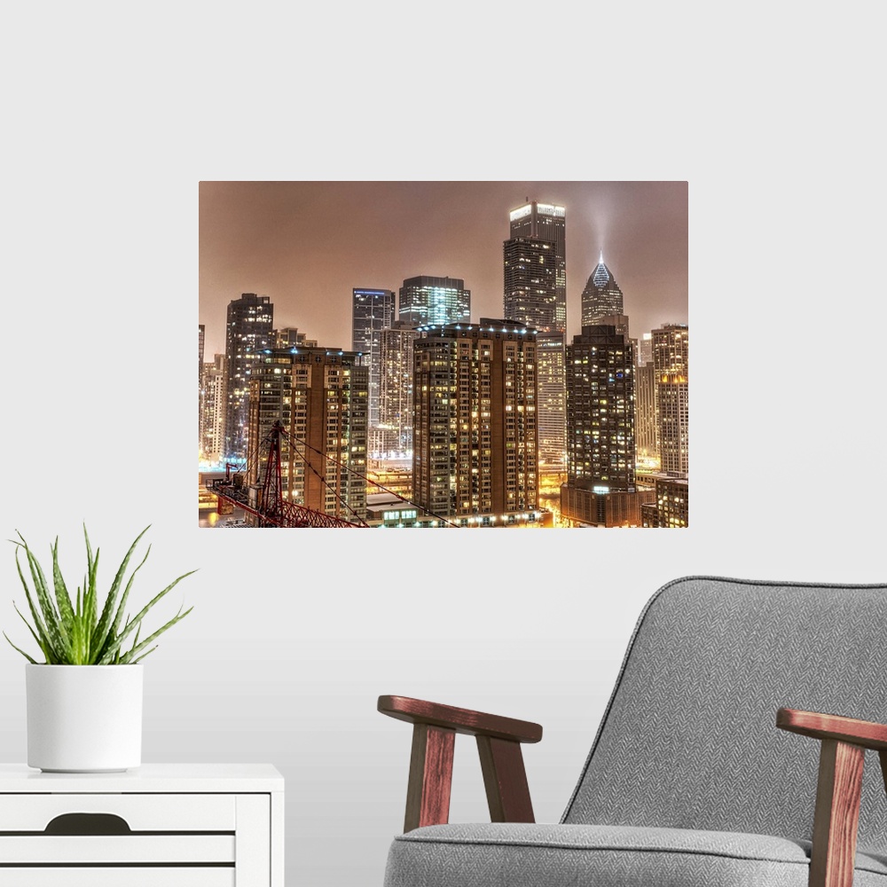 A modern room featuring A photograph taken of the Chicago skyline at night with the buildings illuminated and snow beginn...