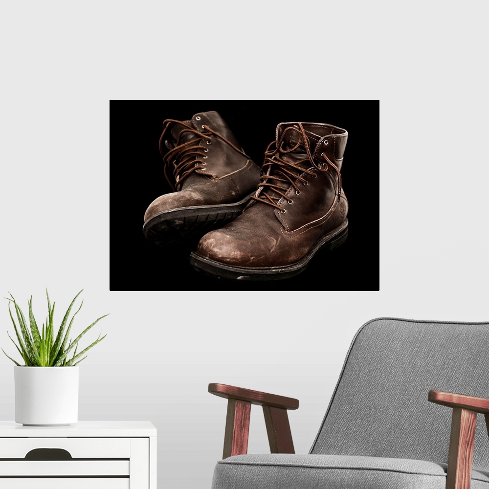 A modern room featuring A pair of well-worn brown boots with laces.