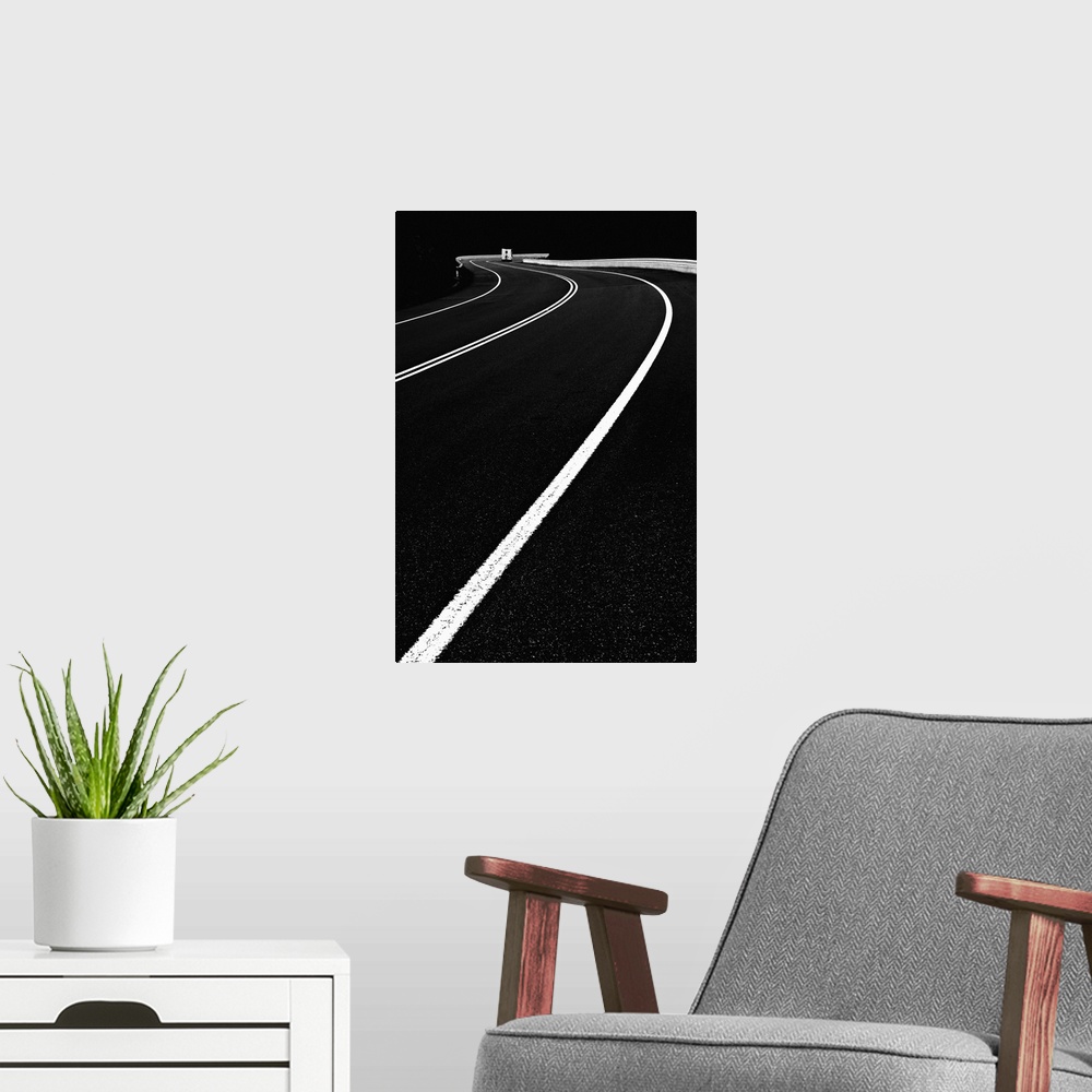 A modern room featuring High contrast black and white image of lines on a road curving around a bend.