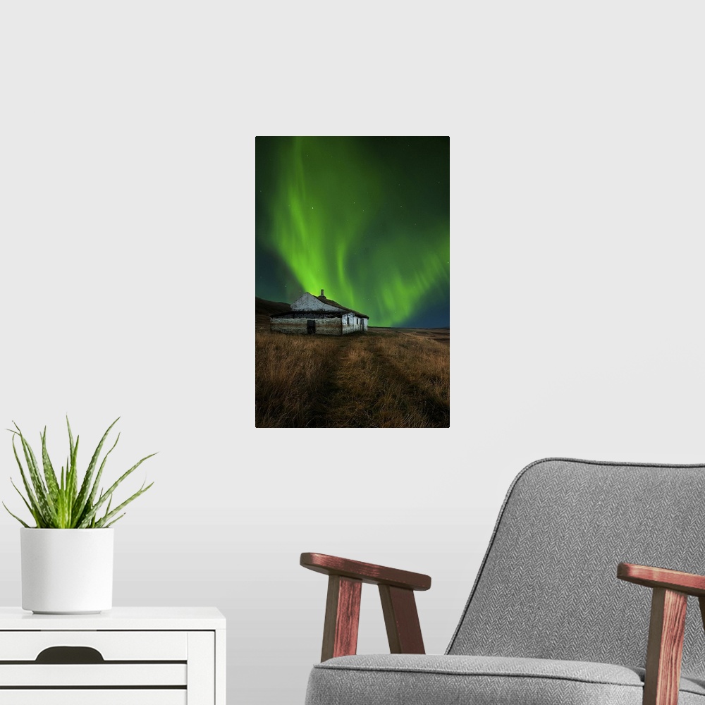 A modern room featuring An abandoned house in a field in Iceland, with a brilliant northern lights display in the skies a...