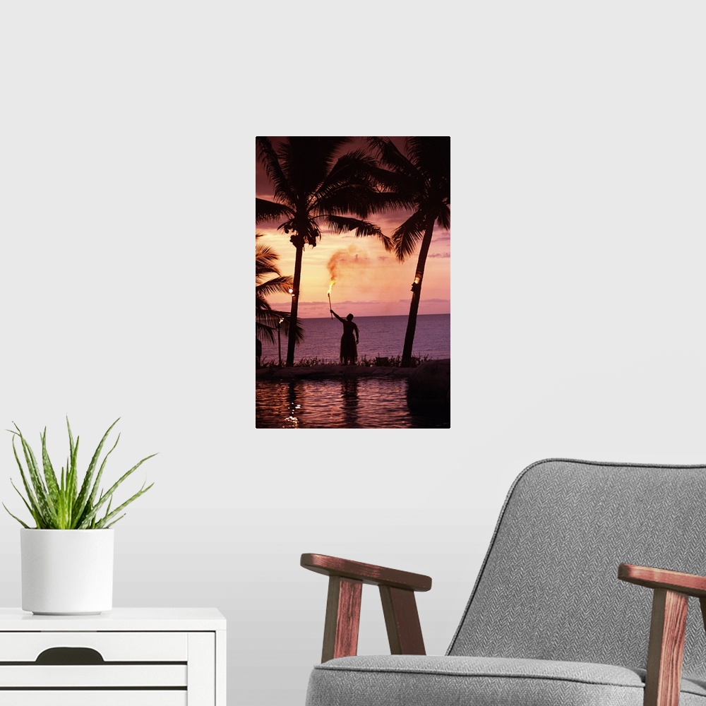 A modern room featuring Native In A Grass Skirt Holding A Flaming Torch By Coast At Sunset