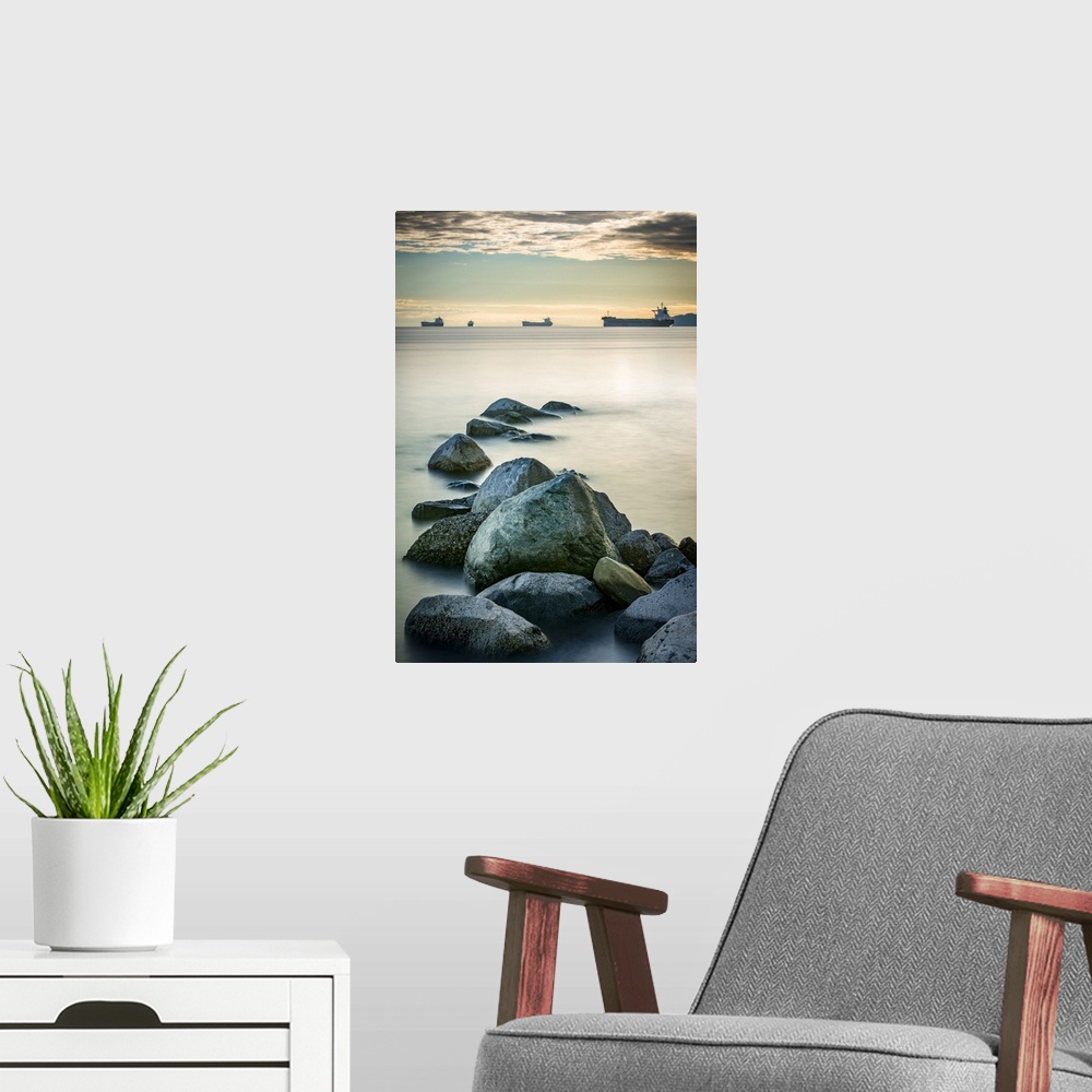 A modern room featuring Ships out in the Pacific ocean off the coast of Stanley Park with rocks in the foreground; Vancou...