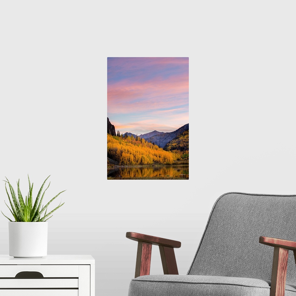 A modern room featuring Landscape photograph of a lake lined with yellow Autumn trees and mountains in the background at ...