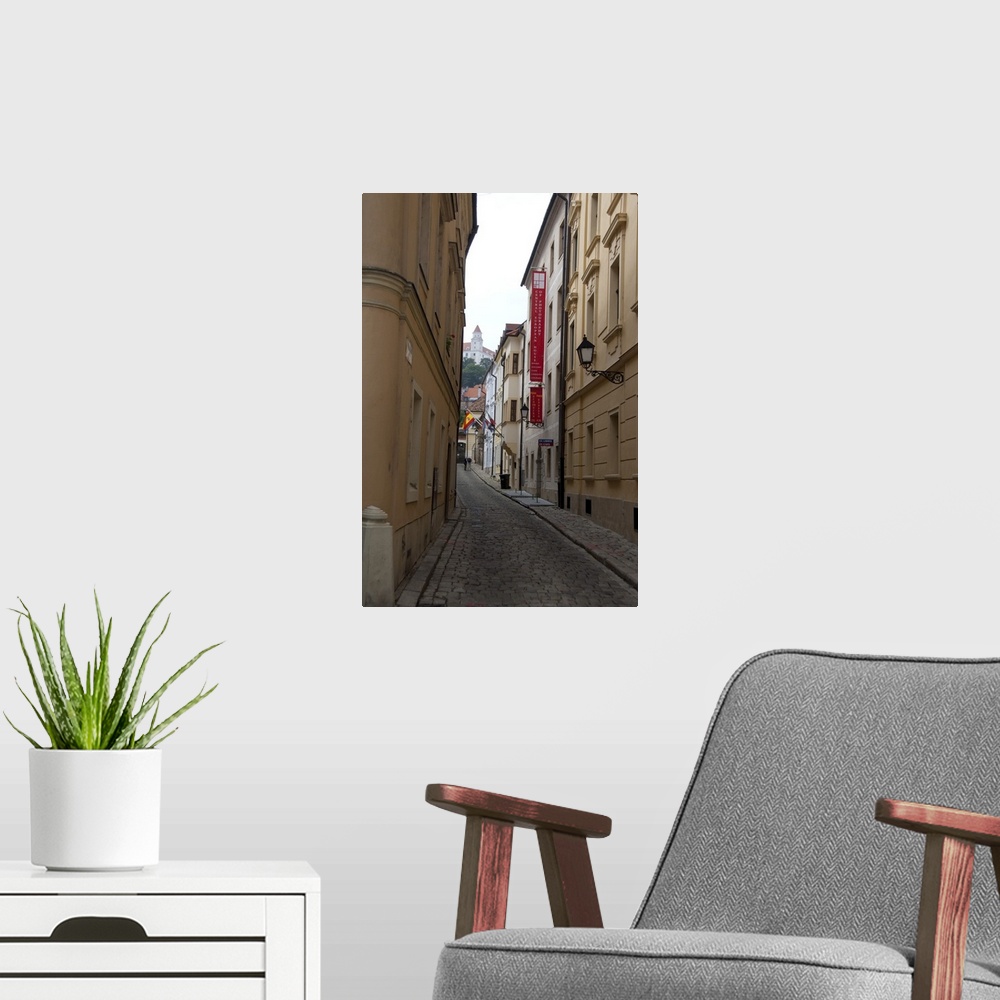 A modern room featuring Slovakia, Bratislava. Narrow street in historic district with view of Bratislava Castle in distance.