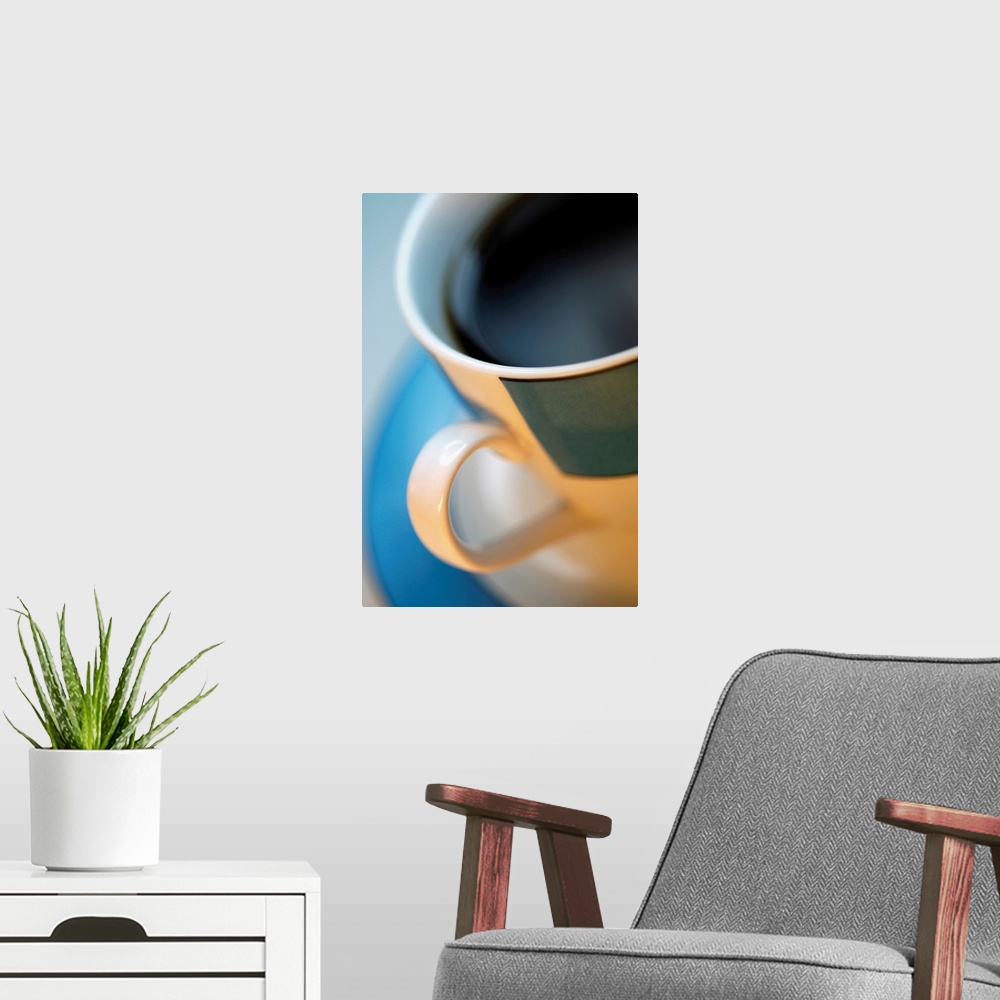 A modern room featuring Extreme close-up of cup of black coffee in tan and black cup with blue saucer