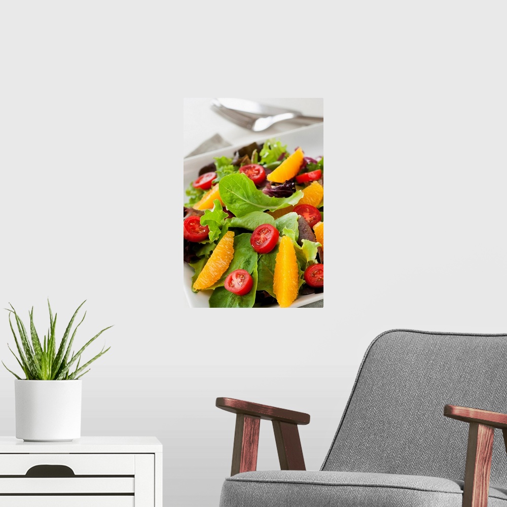 A modern room featuring Leafy greens topped with tomatoes and oranges is elegantly photographed.