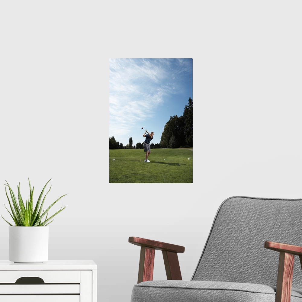 A modern room featuring Golfer swinging club on golf green, side view