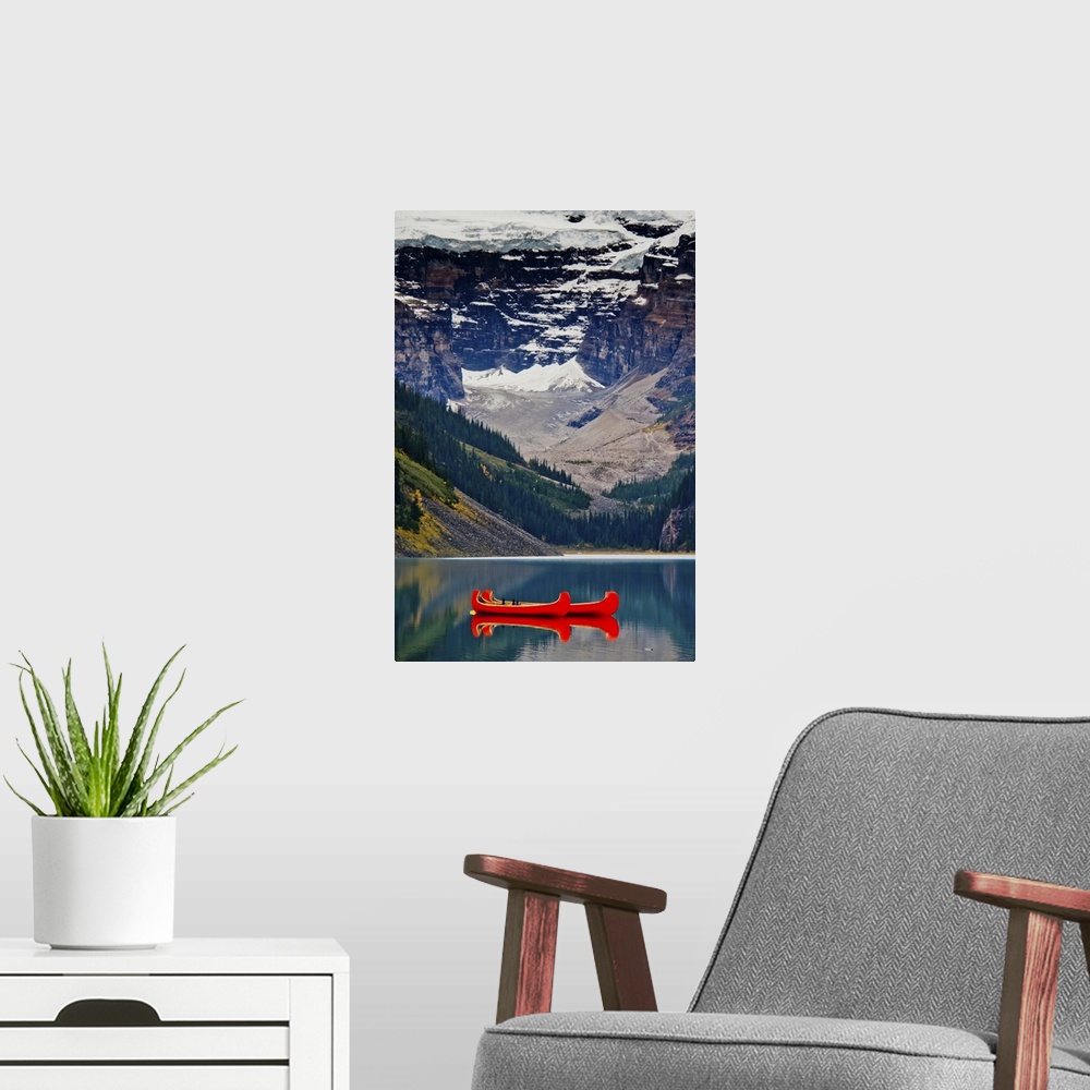 A modern room featuring Lake Louise, British Columbia Canada. Red canoe on the lake in front of glacier & snowy mountains.