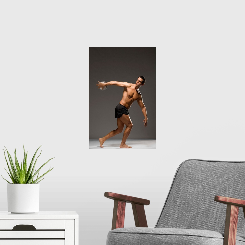 A modern room featuring Male athlete throwing discus, studio shot