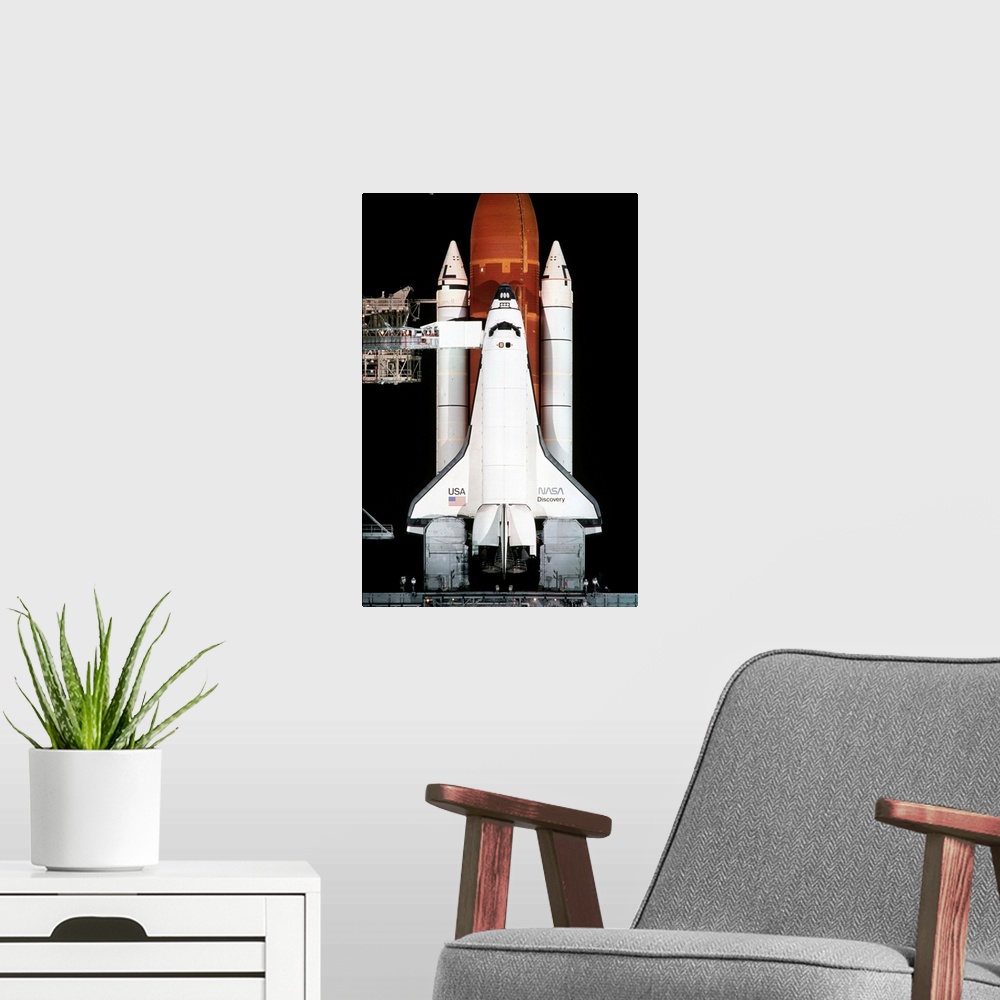 A modern room featuring The space shuttle Discovery sits on the launch pad on the eve of the launch of Space Shuttle Miss...