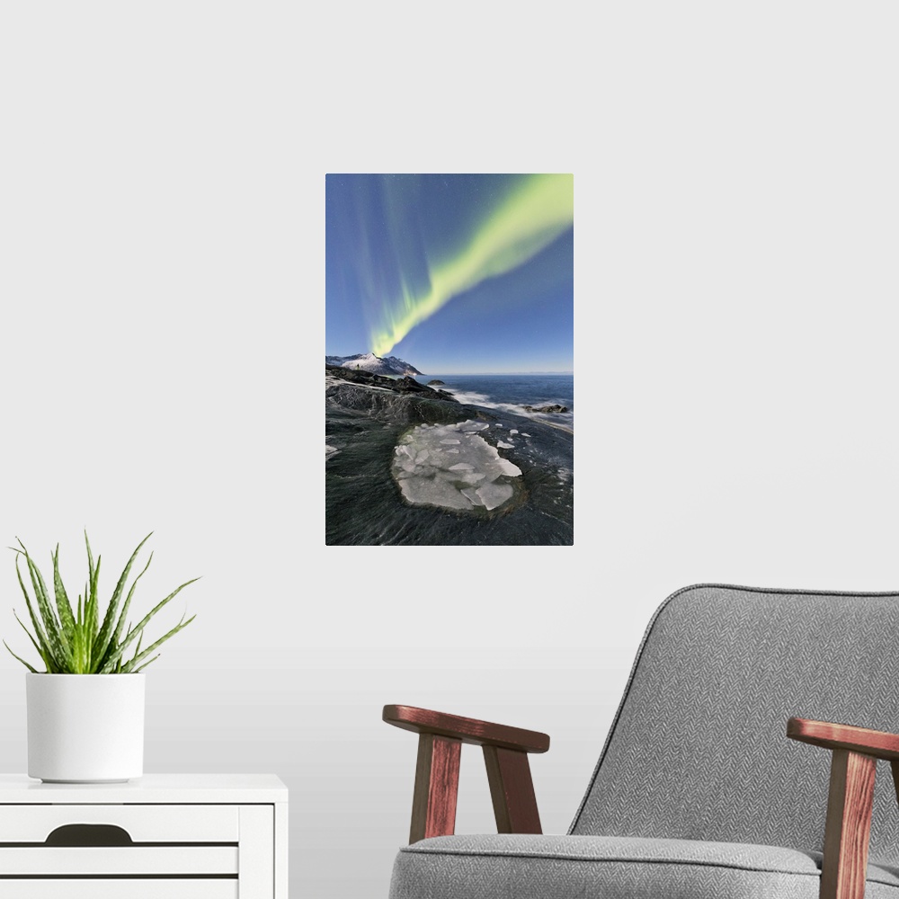 A modern room featuring The Northern Lights illuminates the rocky peaks and icy sea in the polar night Tungeneset Senja T...