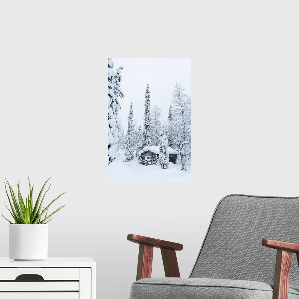 A modern room featuring Wooden hut covered with snow in the snowy forest at Pallas-Yllastunturi National Park, Akaslompol...