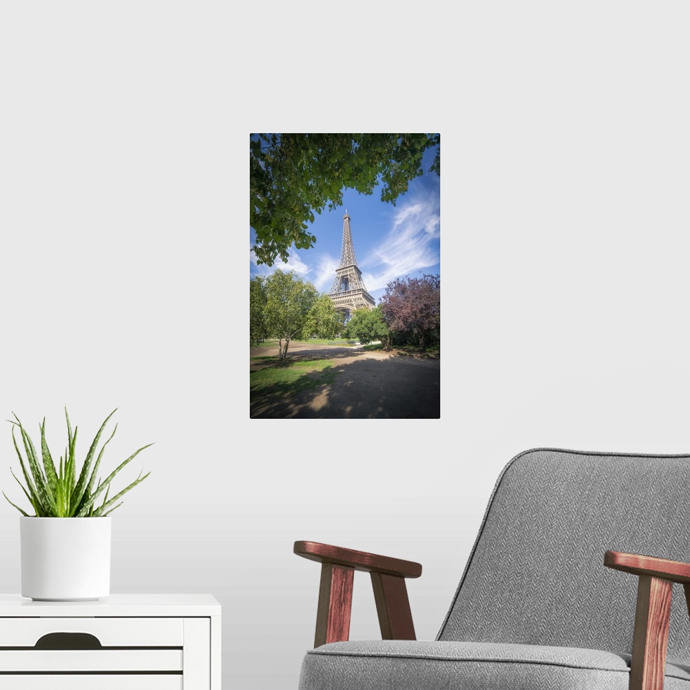A modern room featuring Eiffel tower view from Champ de mars in Paris, France among trees and garden on summer under a bl...