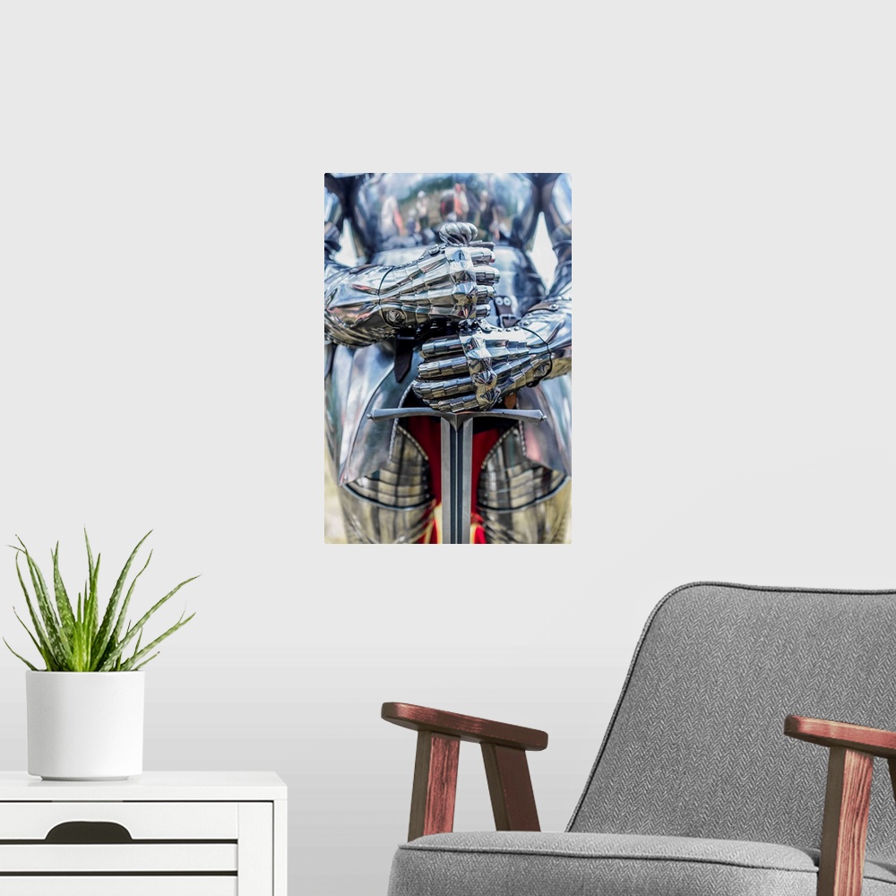 A modern room featuring A photograph of a close-up on a suit of armor holding a sword.