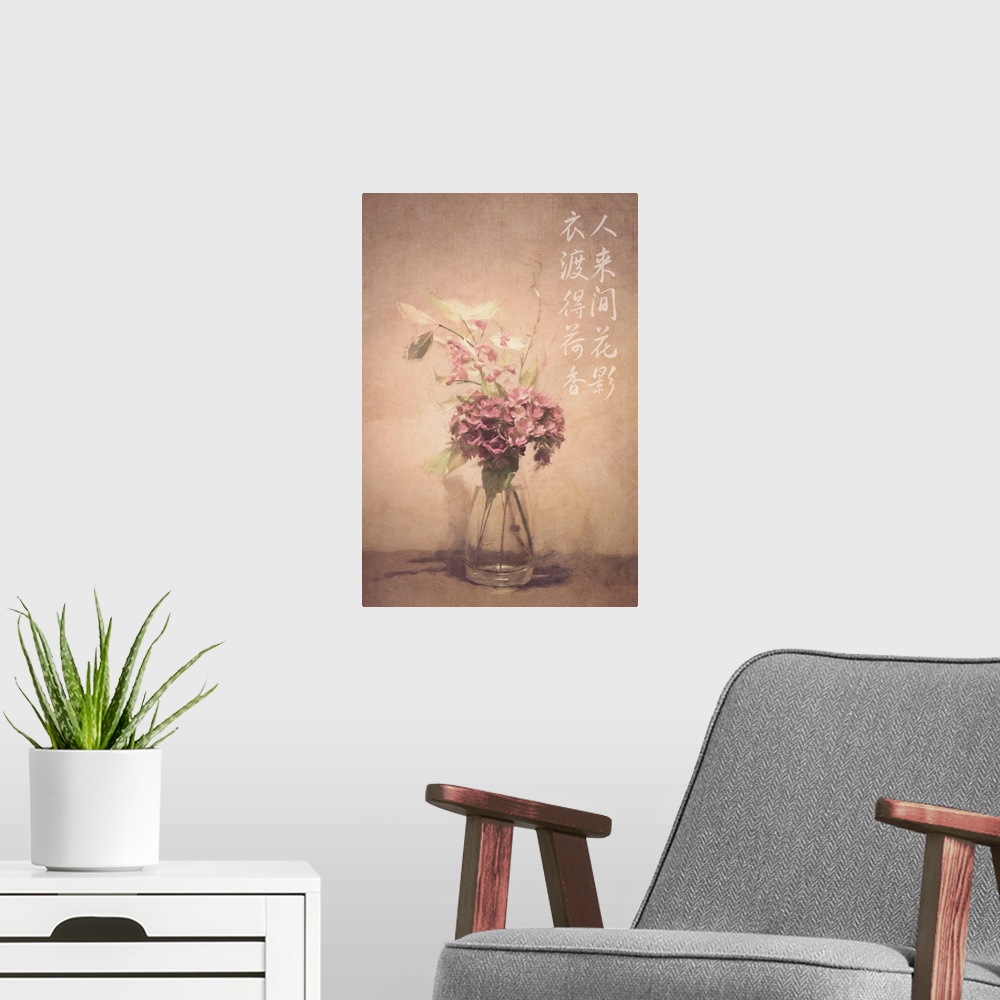 A modern room featuring Asian calligraphy on a wall beside dusty pink and white flowers in a clear glass vase.