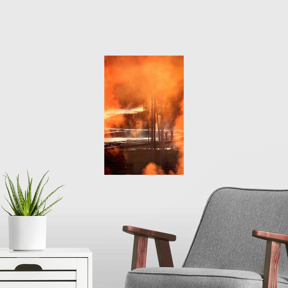 A modern room featuring A photo of orange smoke clouds obscuring a view of Yellowstone park and two patrons.