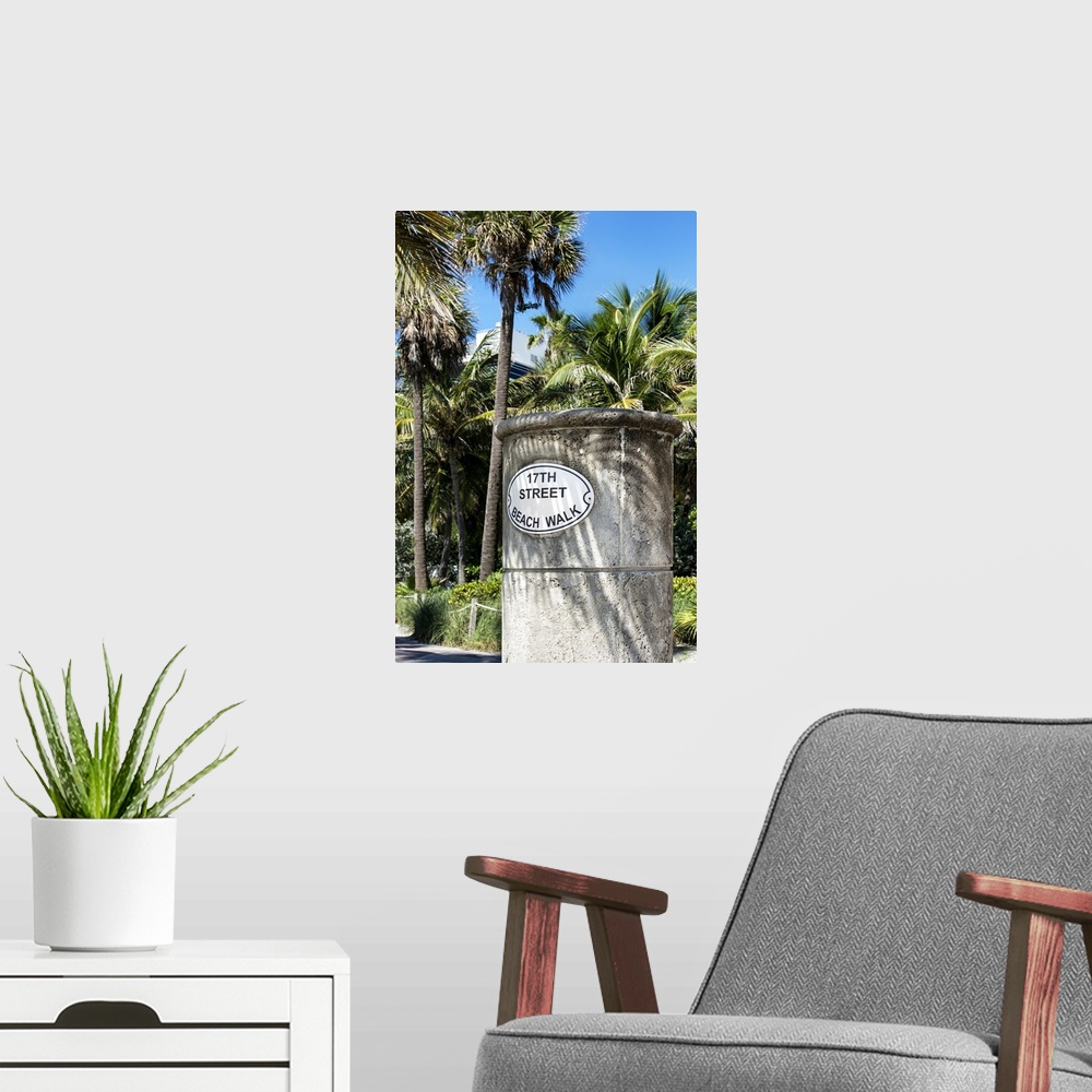 A modern room featuring A stone sign for the Beach Walk in Miami, shaded by palm trees.