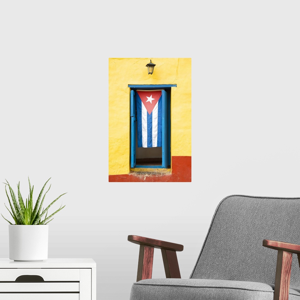 A modern room featuring Photograph of the Cuban flag hanging in a window on a yellow and red wall in Havana.