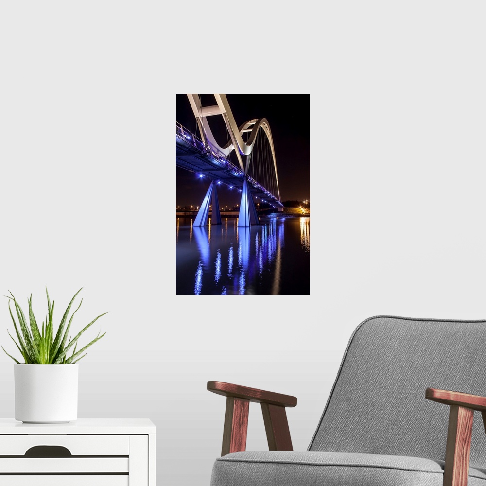 A modern room featuring Infinity Bridge with bright blue lights reflected in the water, Stockton on Tees, England.