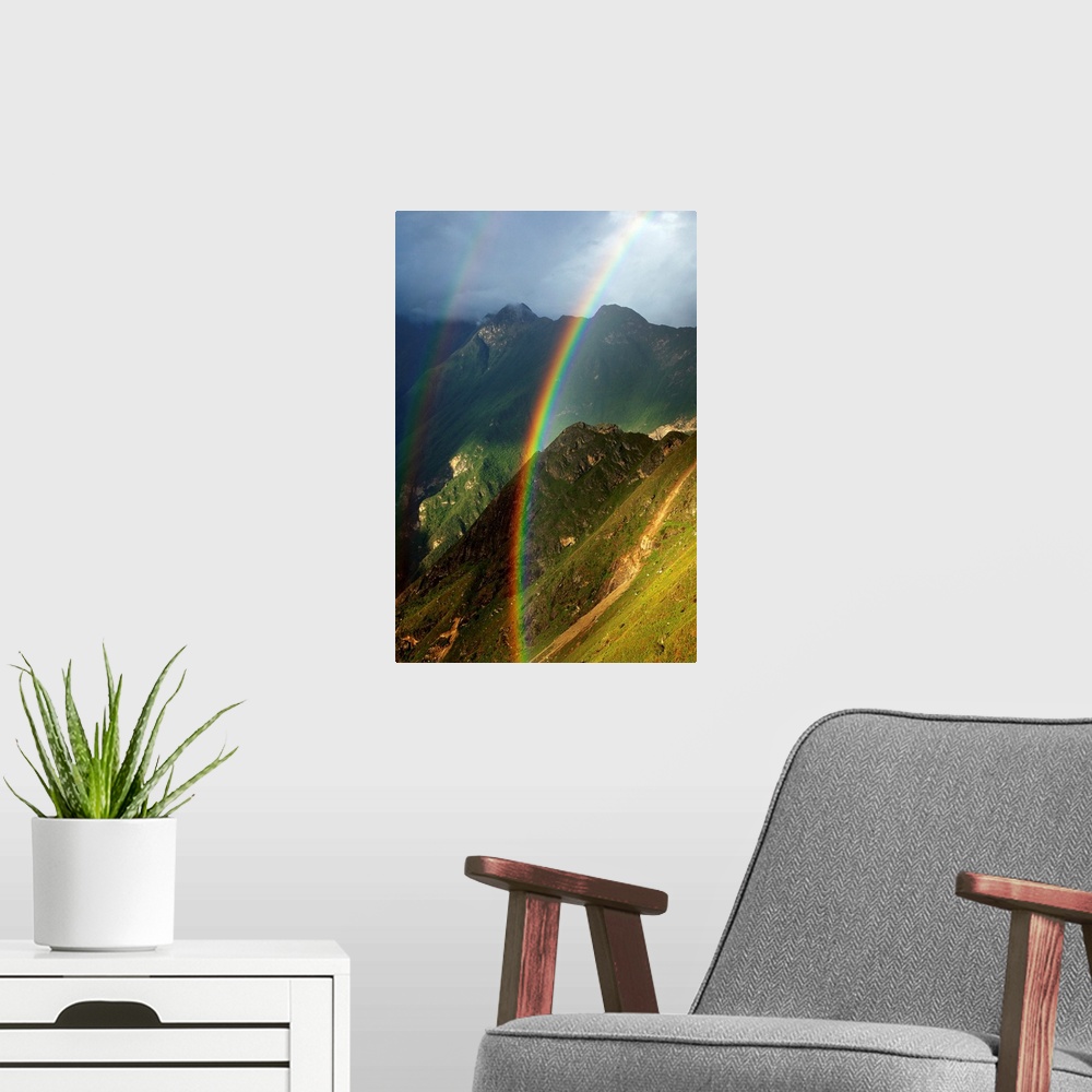 A modern room featuring Vertical photograph of a double rainbow over green mountains on a cloudy day.