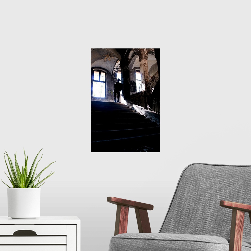 A modern room featuring Silhouette of a man standing on some old stairs in a large building