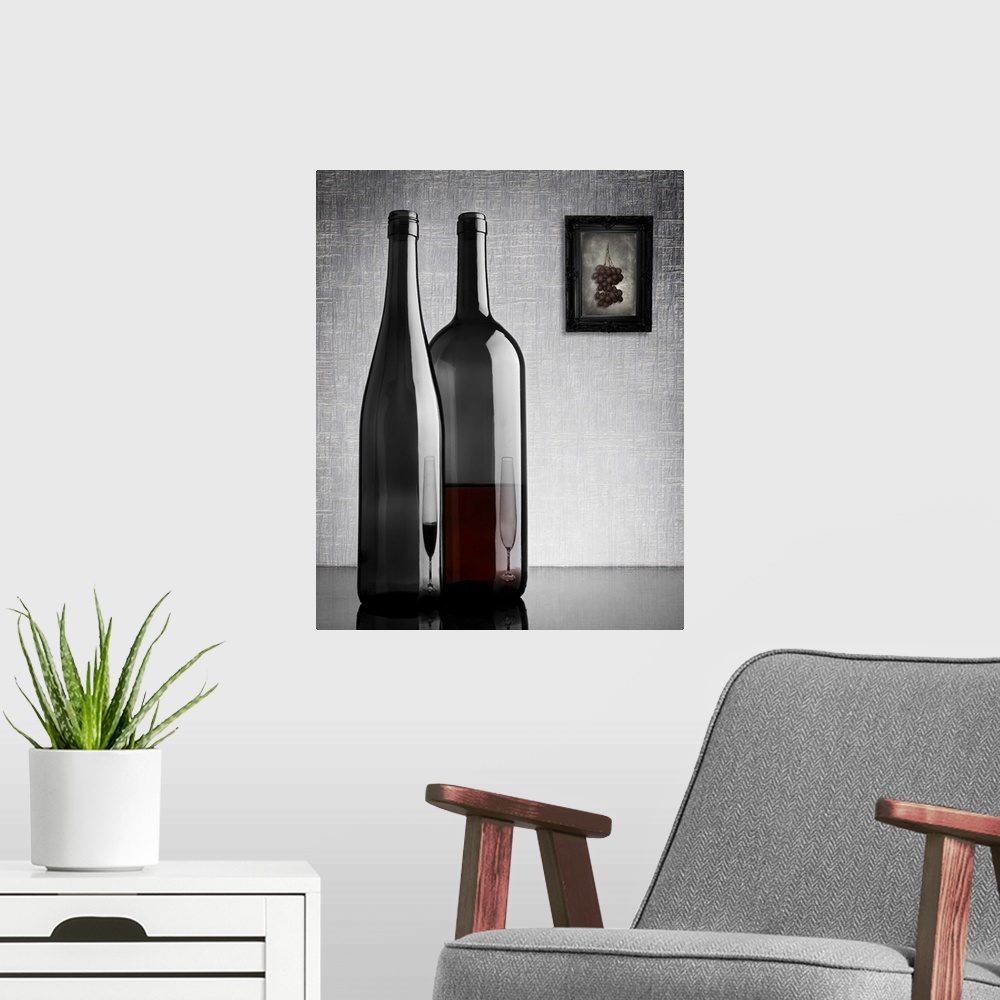 A modern room featuring Two glass wine bottles with reflections of glasses on them, and a framed image of grapes on the w...