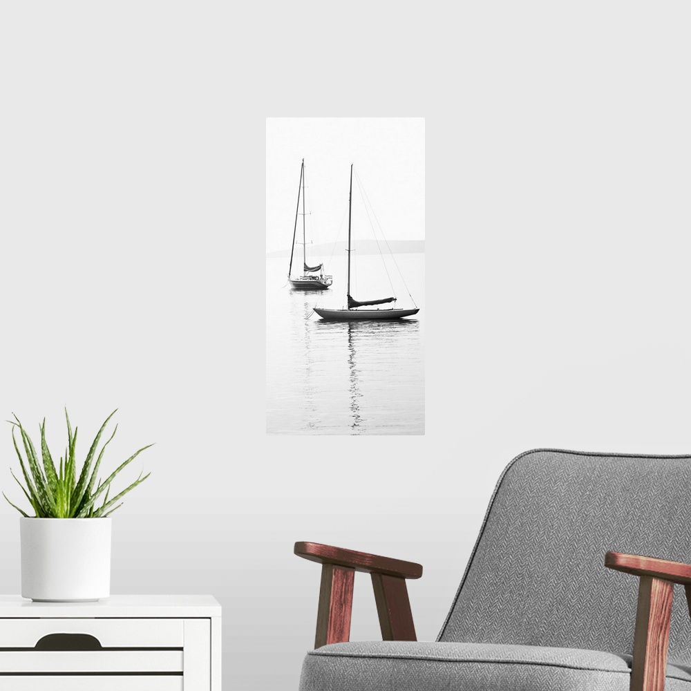 A modern room featuring Black and white photograph of two sailboats with sails down on calm water.