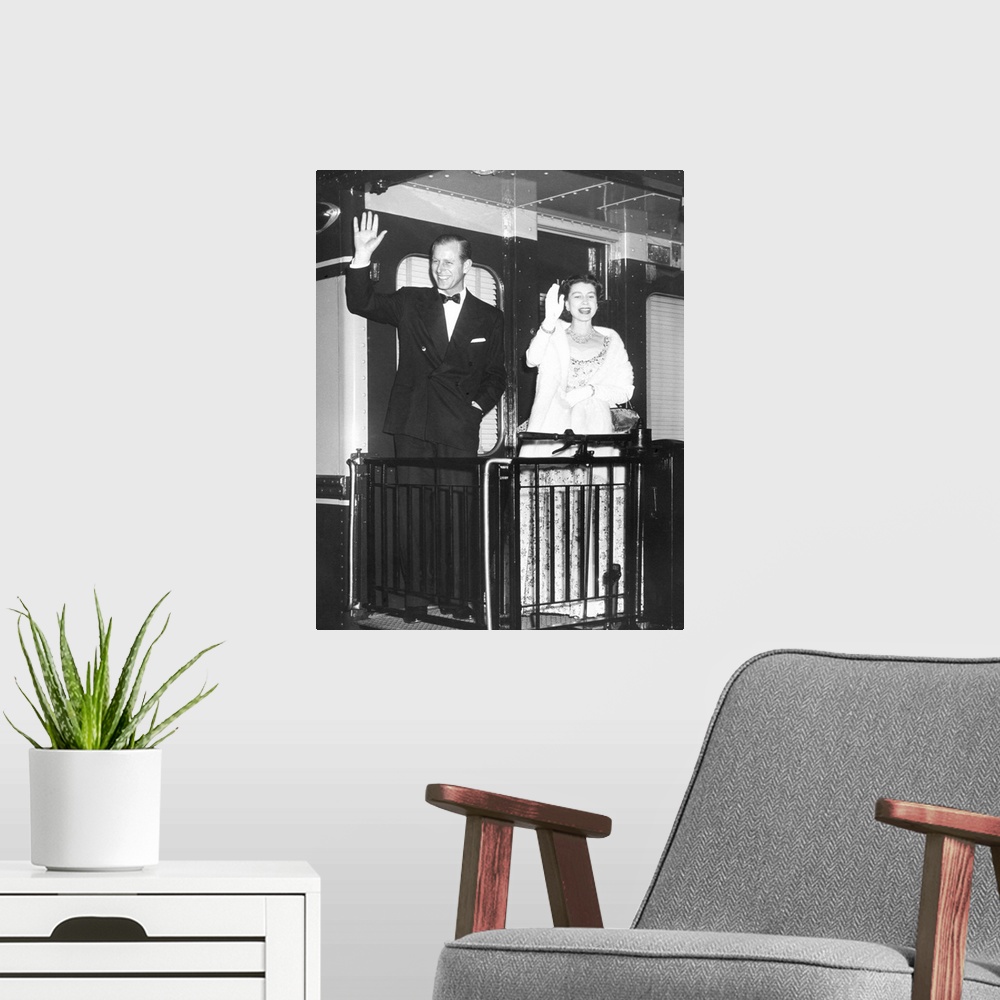 A modern room featuring Queen Elizabeth II and Prince Philip wave from the back of a train at Union Station. After entert...