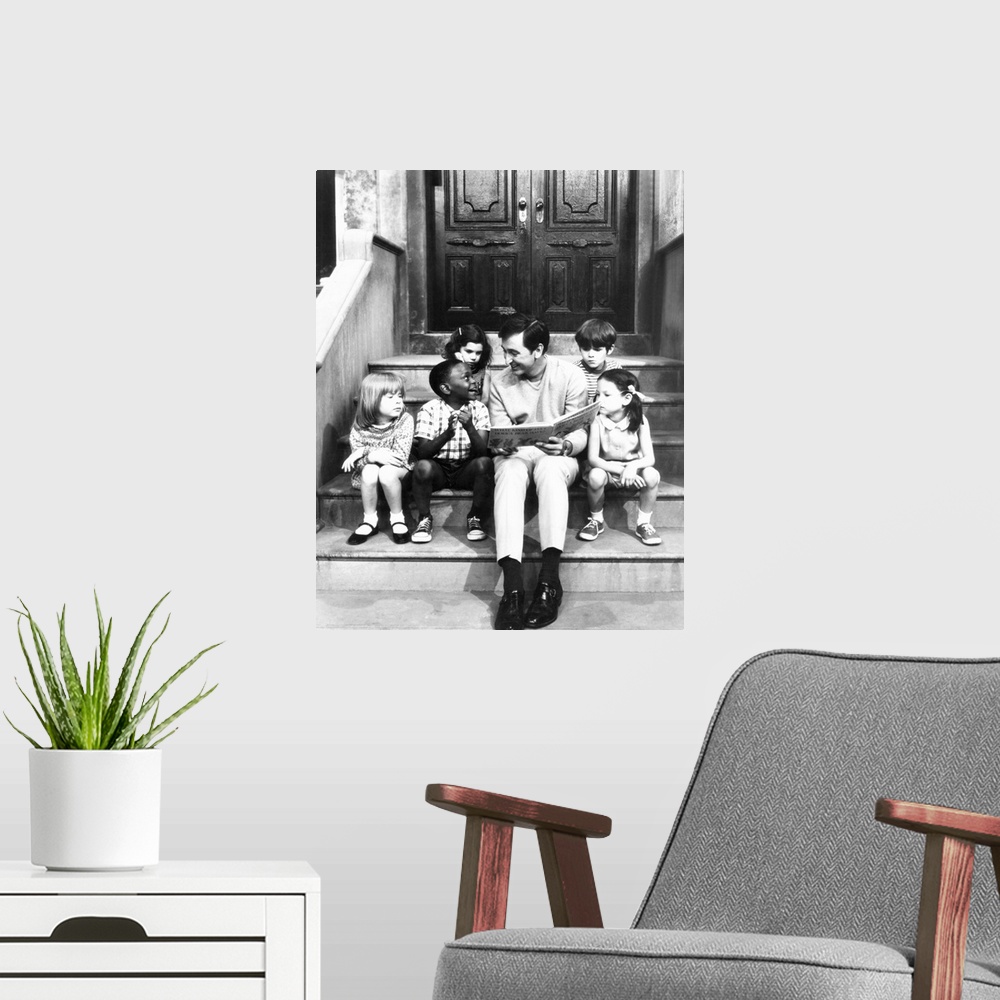 A modern room featuring Robert Emmet McGrath, as character Bob Johnson, reading to children on Sesame Street, 1970.