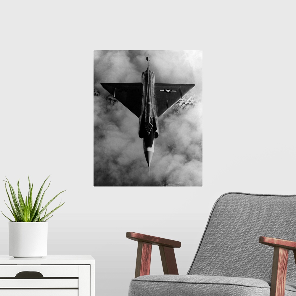 A modern room featuring A United States Air Force, delta-wing F-102A, interceptor aircraft in flight above cloud cover.