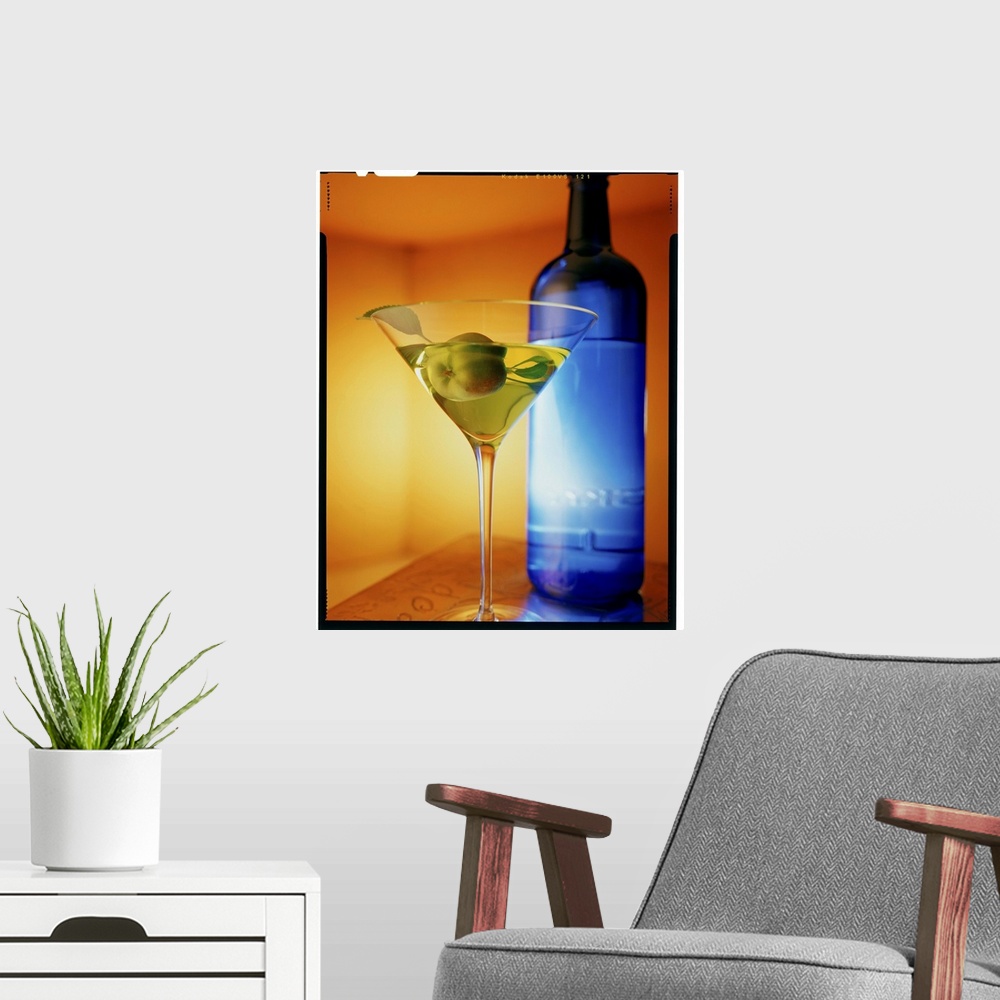 A modern room featuring Big vertical photograph of fruit martini in a glass, sitting on a counter in front of a blue bottle.
