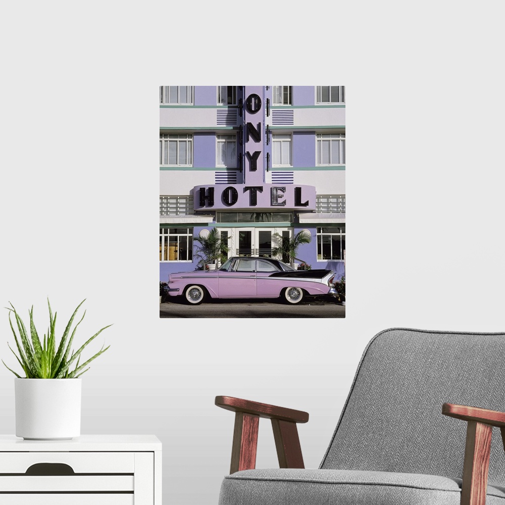 A modern room featuring Vertical photograph on a large wall hanging of an old, classic car parked beneath the sign for th...