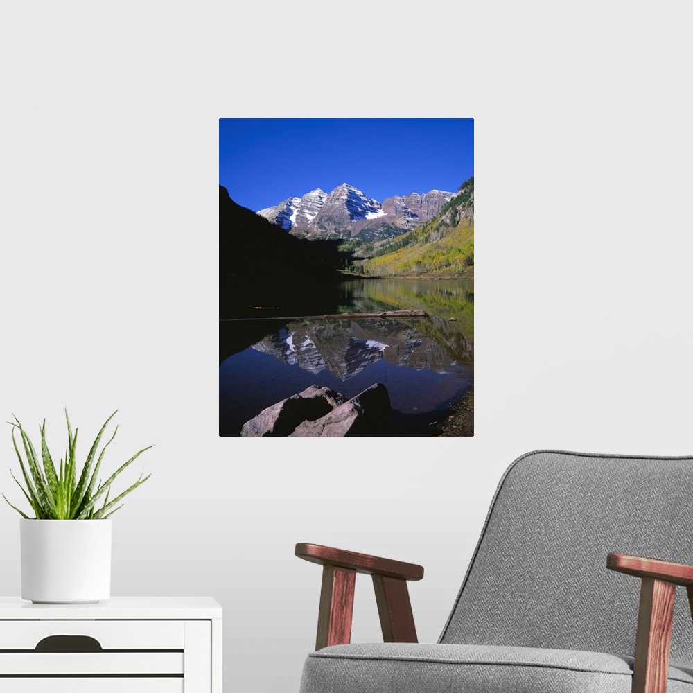 A modern room featuring Calm photograph of snowy mountain peaks in the Rocky Mountains, reflected in a still lake of fres...